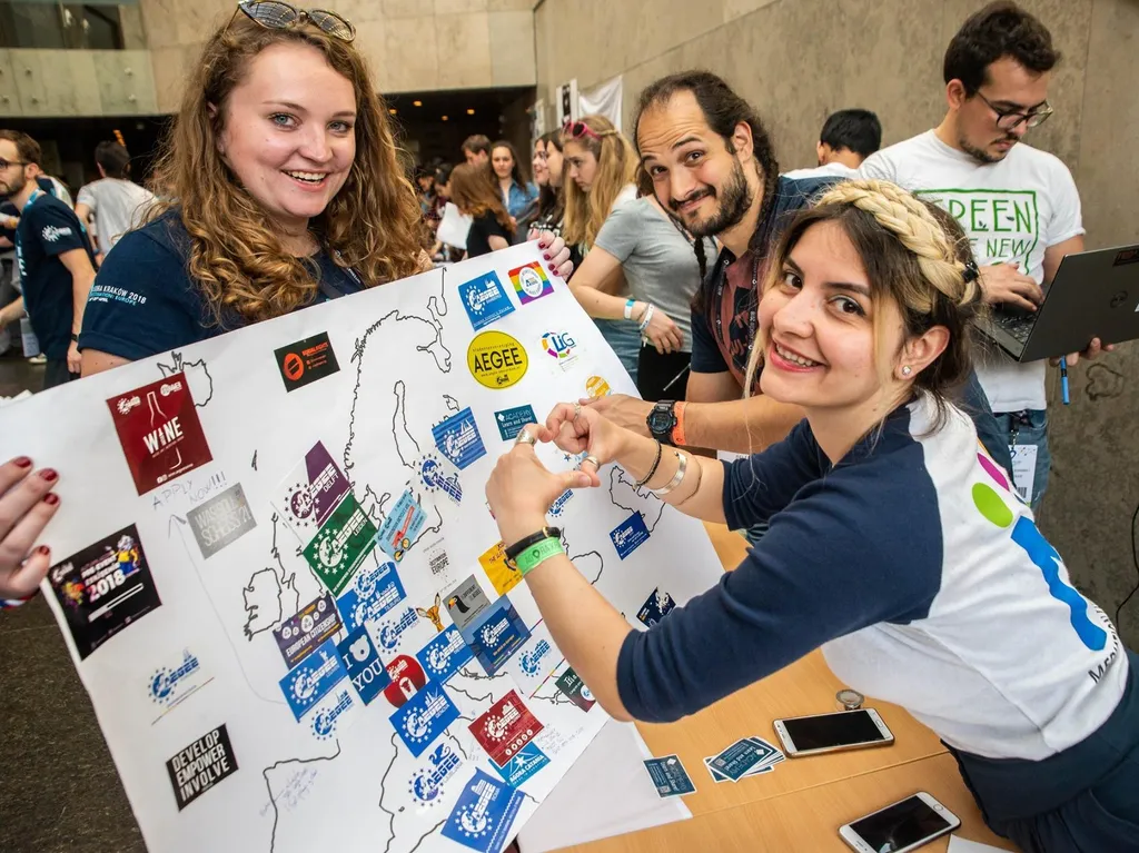 Leden uit het AEGEE-netwerk met een kaart vol stickers van verschillende AEGEE-verenigingen.