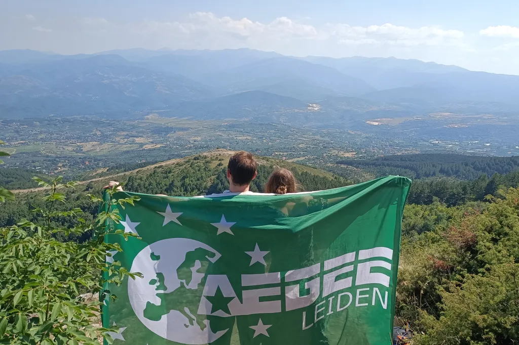 Twee AEGEE-Leiden leden die samen de verenigingsvlag vasthouden.