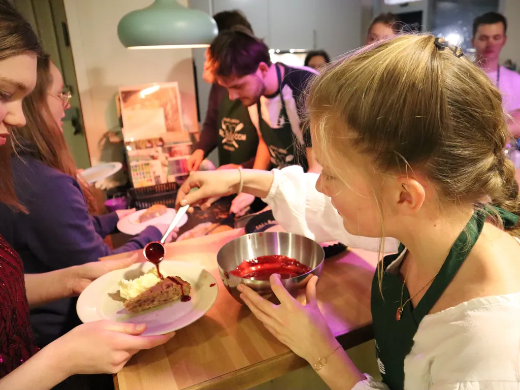 Een lid van de kookcommissie schept eten op tijdens het benefietdiner.